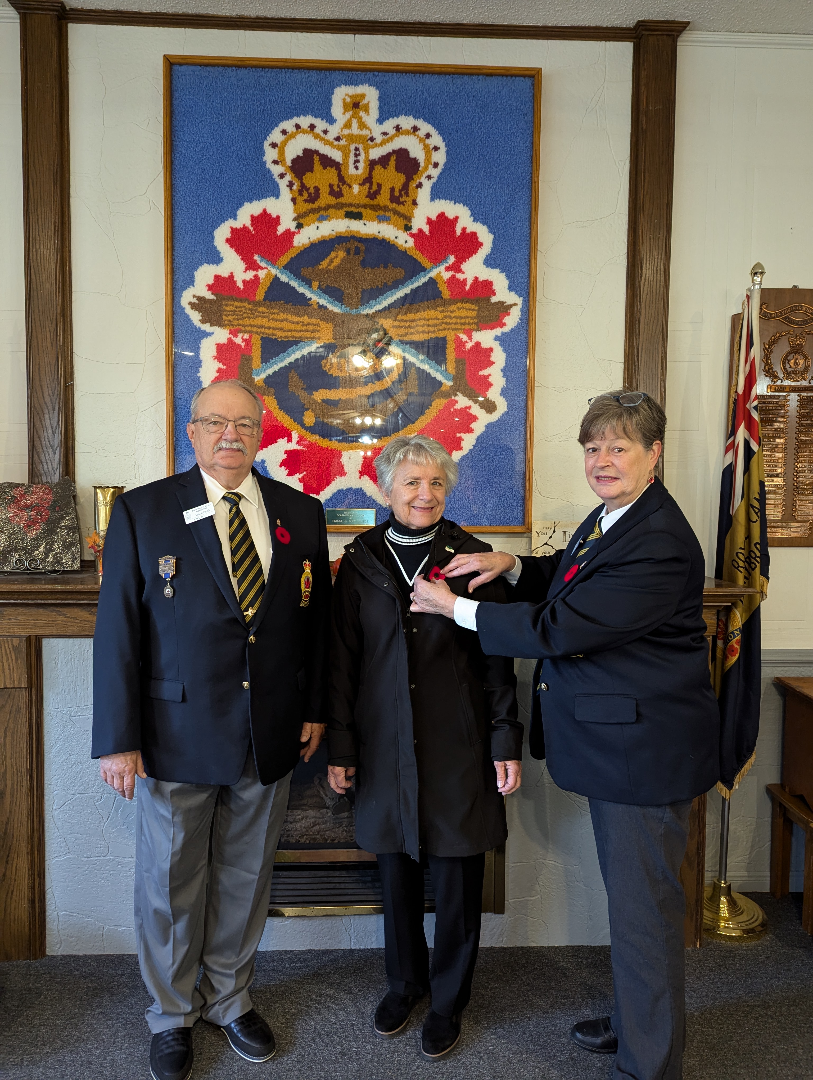 Donnybrook Legion President Shane Lynch, Mayor McMillan and Poppy Chairperson Sjouk Lynch standing in front of air force logo and Sjouk Lynch pining poppy on Mayor. 